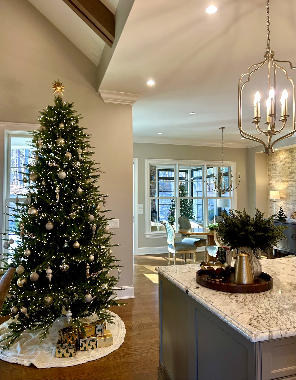 A tall Christmas tree with warm lights beside bright windows in a Triangle home styled by Signature Porch Decor