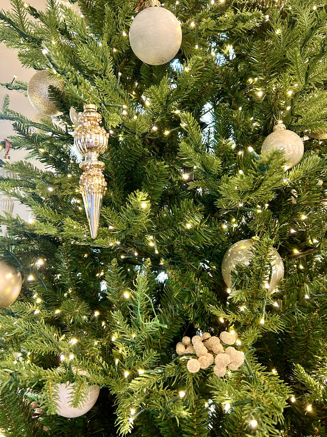 White and silver ornaments with warm lights on a Christmas tree